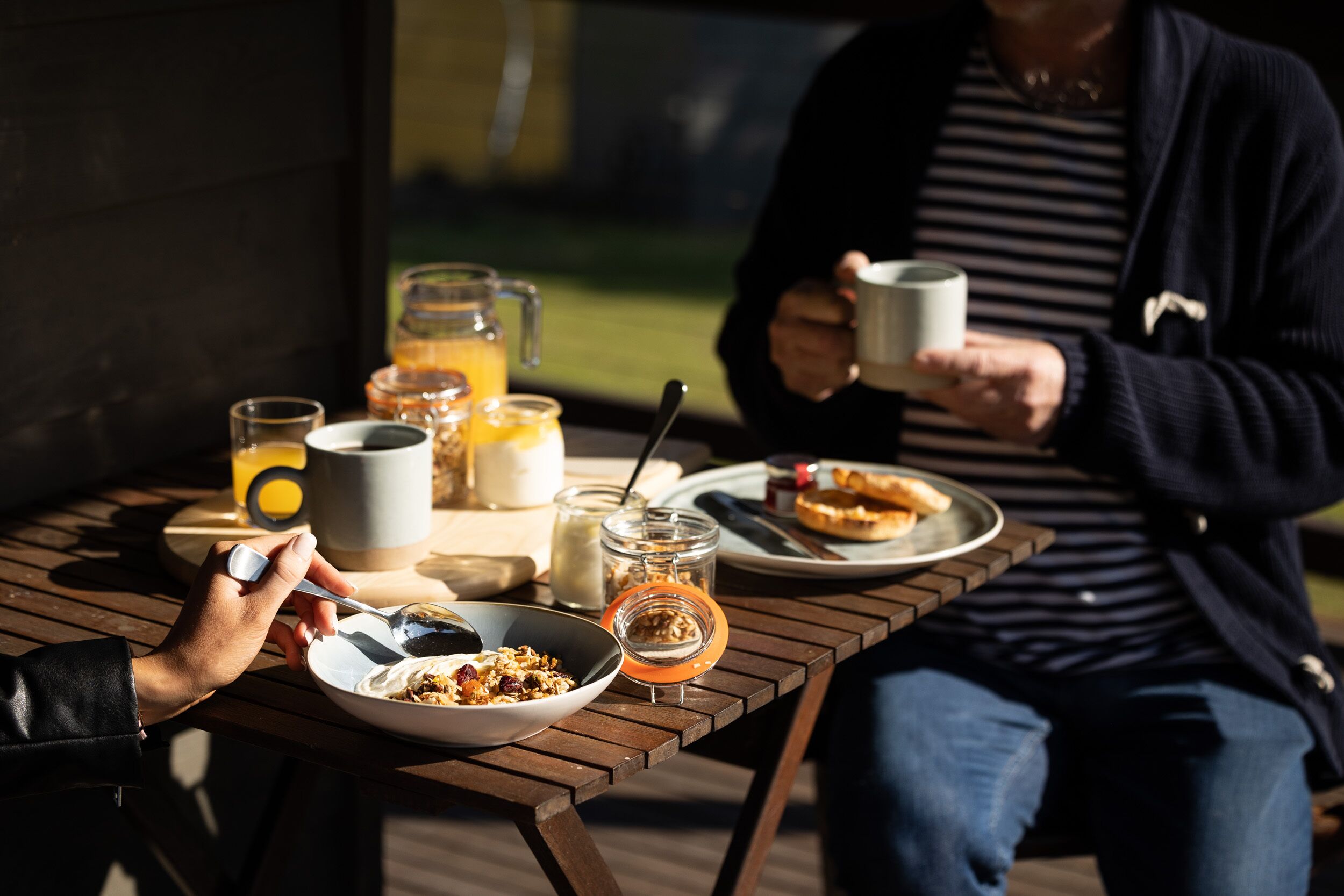 Una mesa de madera con alimentos para el desayuno, incluyendo cereal, tostadas y una bebida.