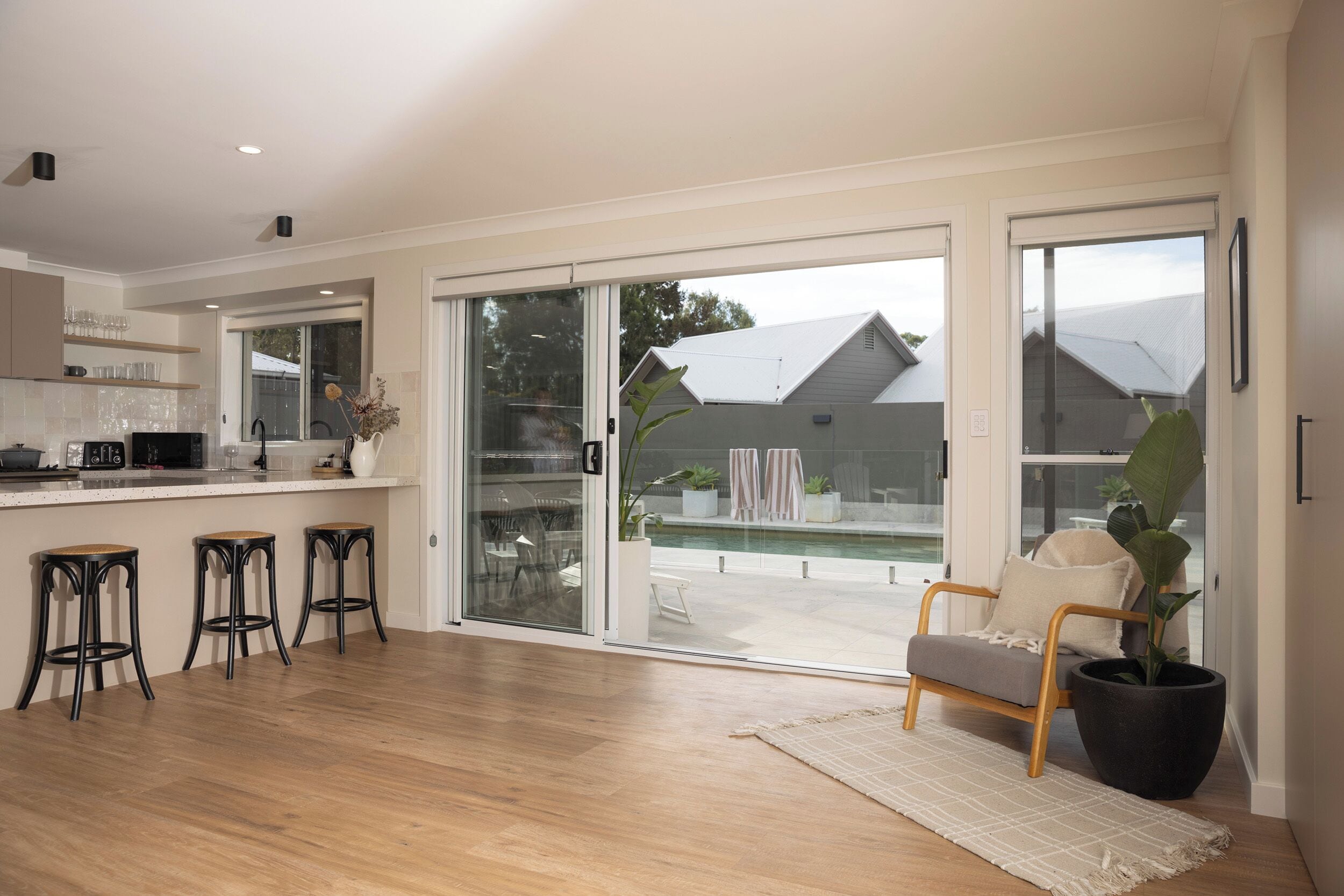 A modern kitchen with a bar area, large sliding glass doors leading to a patio, and a seating area with a plant.