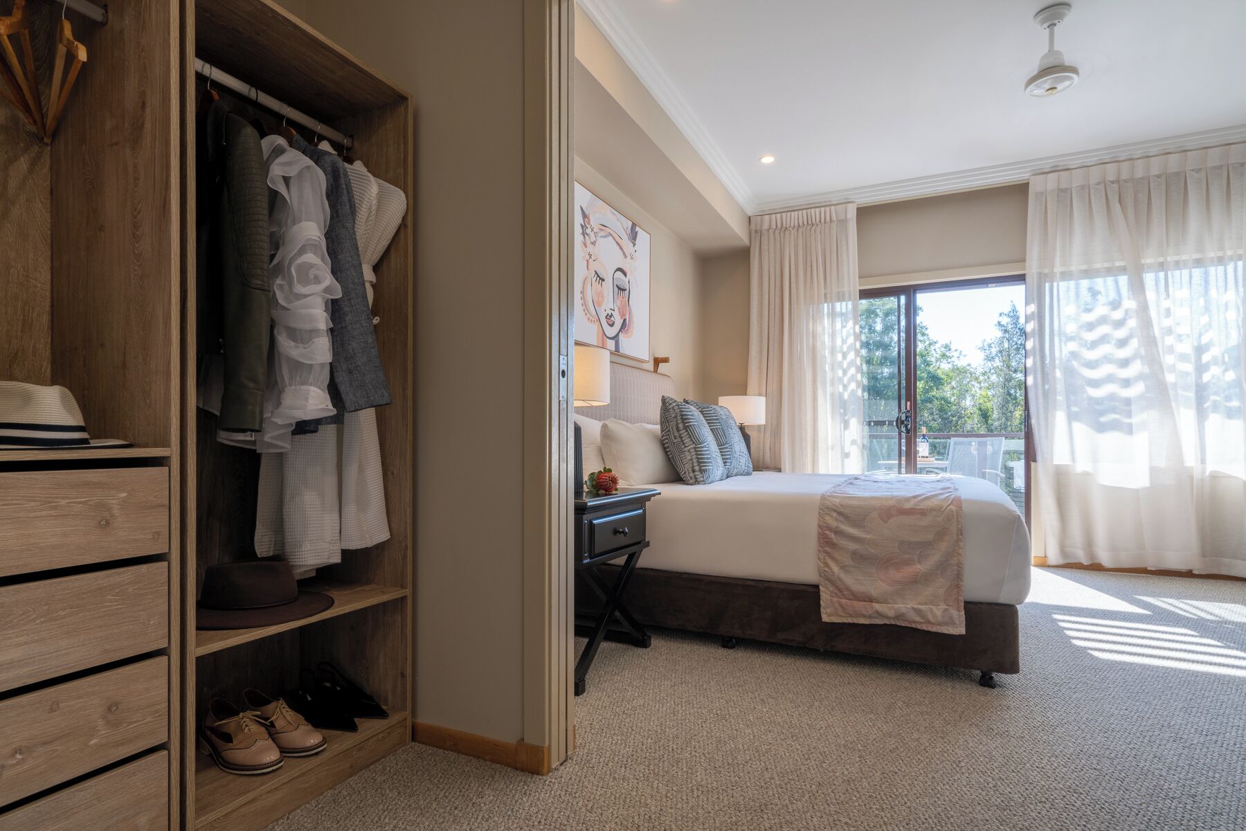 A bedroom with a large bed, a wardrobe, and a desk with a lamp.