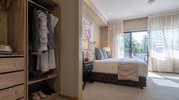 A bedroom with a large bed, a wardrobe, and a desk with a lamp.