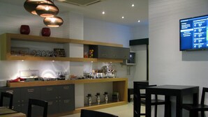 Eine moderne Küche mit Holzböden, eine Essecke mit schwarzen Stühlen und ein an der Wand befestigter Flachbildfernseher.