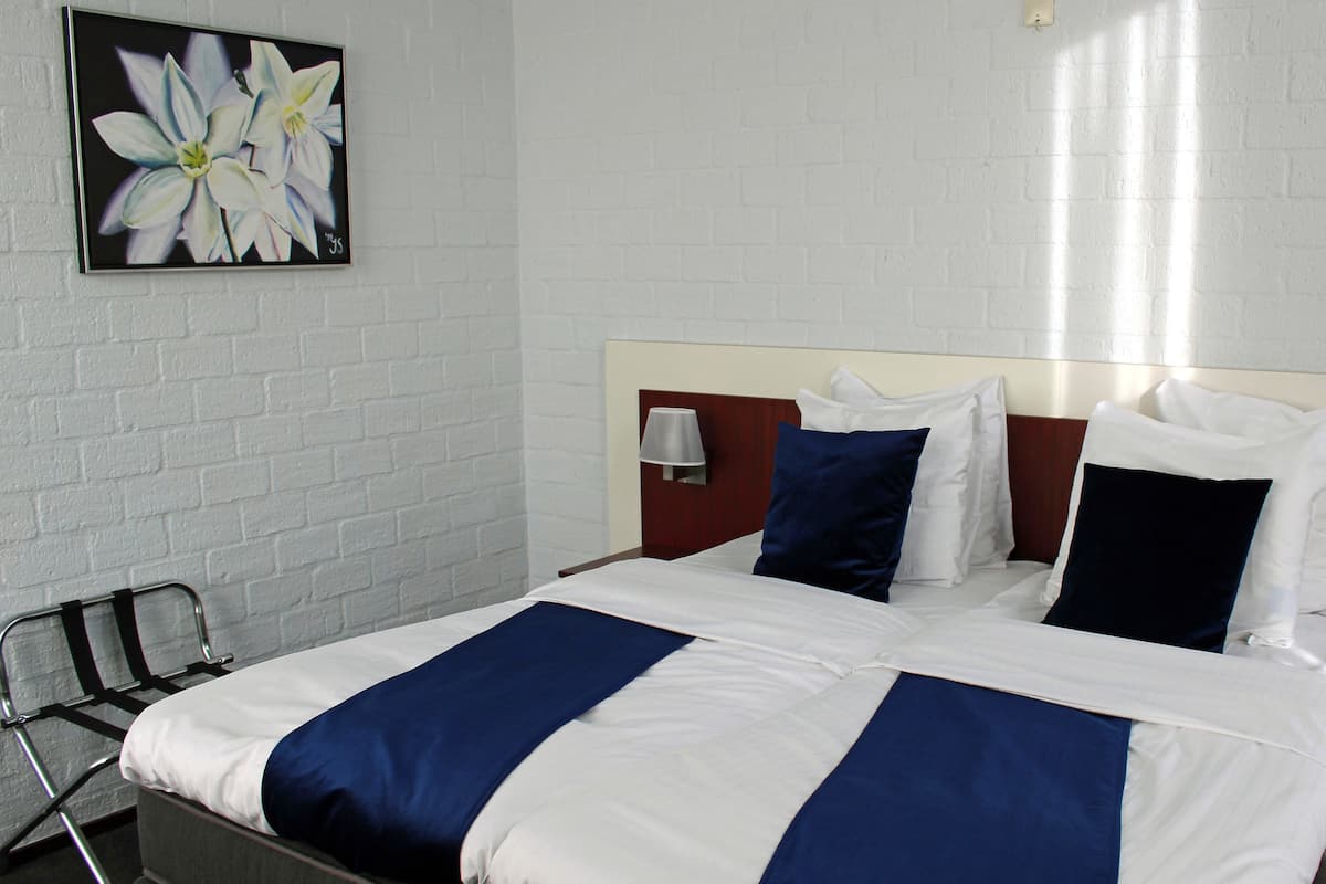 A hotel room with a bed, two bedside tables, a chair, and a wall-mounted lamp.