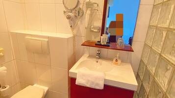 Un bany amb vàter, un lavabo amb mirall i una zona de dutxa.