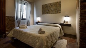 A bedroom with a large bed, stone wall, and a stone fireplace. - Az Agrituristica Bio Le Macchie Alte (Manciano)