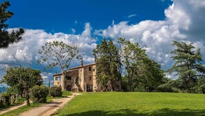 A stone building with a rustic appearance, surrounded by lush greenery and trees. - Az Agrituristica Bio Le Macchie Alte (Manciano)