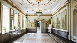 A grand hallway with a patterned floor, large mirrors, and a classical ceiling design.