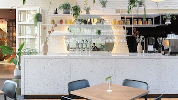 Zona de bar moderna con una encimera veteada, plantas colgantes y una máquina de café.