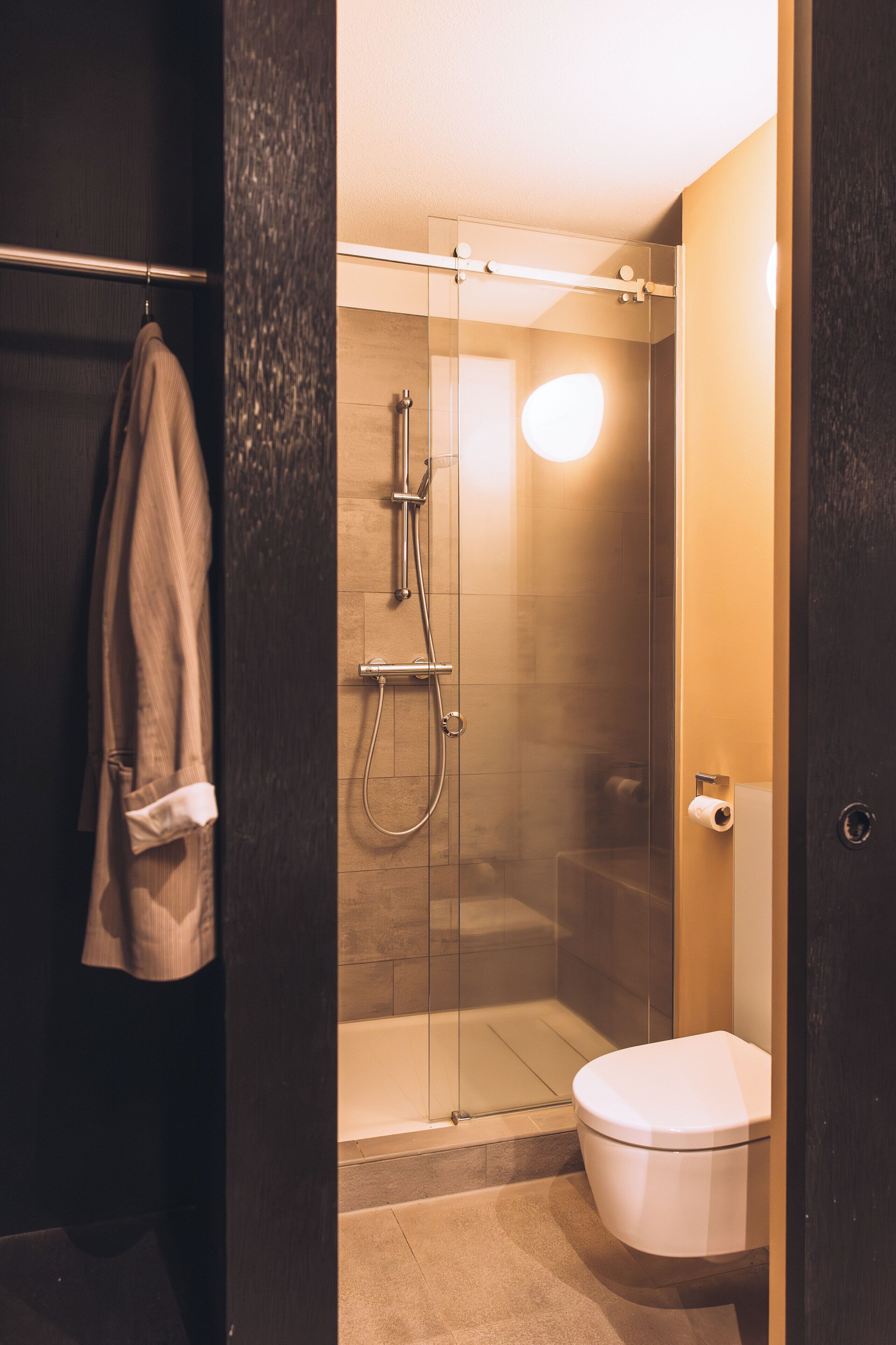 A modern bathroom with a glass-enclosed shower, a white toilet, and a towel rack.