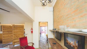 A cozy room with a stone floor, a red chair, a wooden partition, a TV, and a fireplace with a framed picture. - motel Mi Pi CHi (Johannesburg)