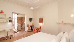A bedroom with a bed, a desk, a chair, and a television. There is a door leading to a bathroom and a kitchen. - motel Mi Pi CHi (Johannesburg)