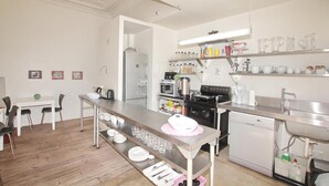 A modern kitchen with stainless steel appliances, a dining area with chairs and a table, and a well-organized countertop with various kitchen items. - motel Mi Pi CHi (Johannesburg)