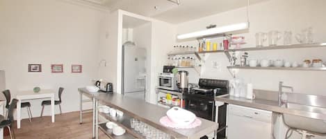 Una cocina moderna con electrodomésticos de acero inoxidable, una zona de comedor con sillas y una mesa, y una encimera bien organizada con diversos utensilios de cocina.