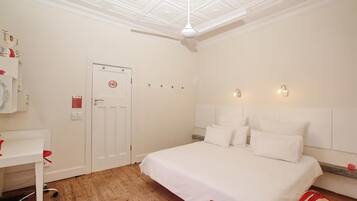Una habitación de hotel con cama, escritorio y ventilador de techo.