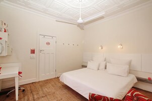 Una habitación de hotel con cama, escritorio y ventilador de techo.