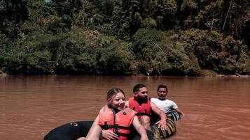 Tres personas en un bote en un río rodeado de árboles.