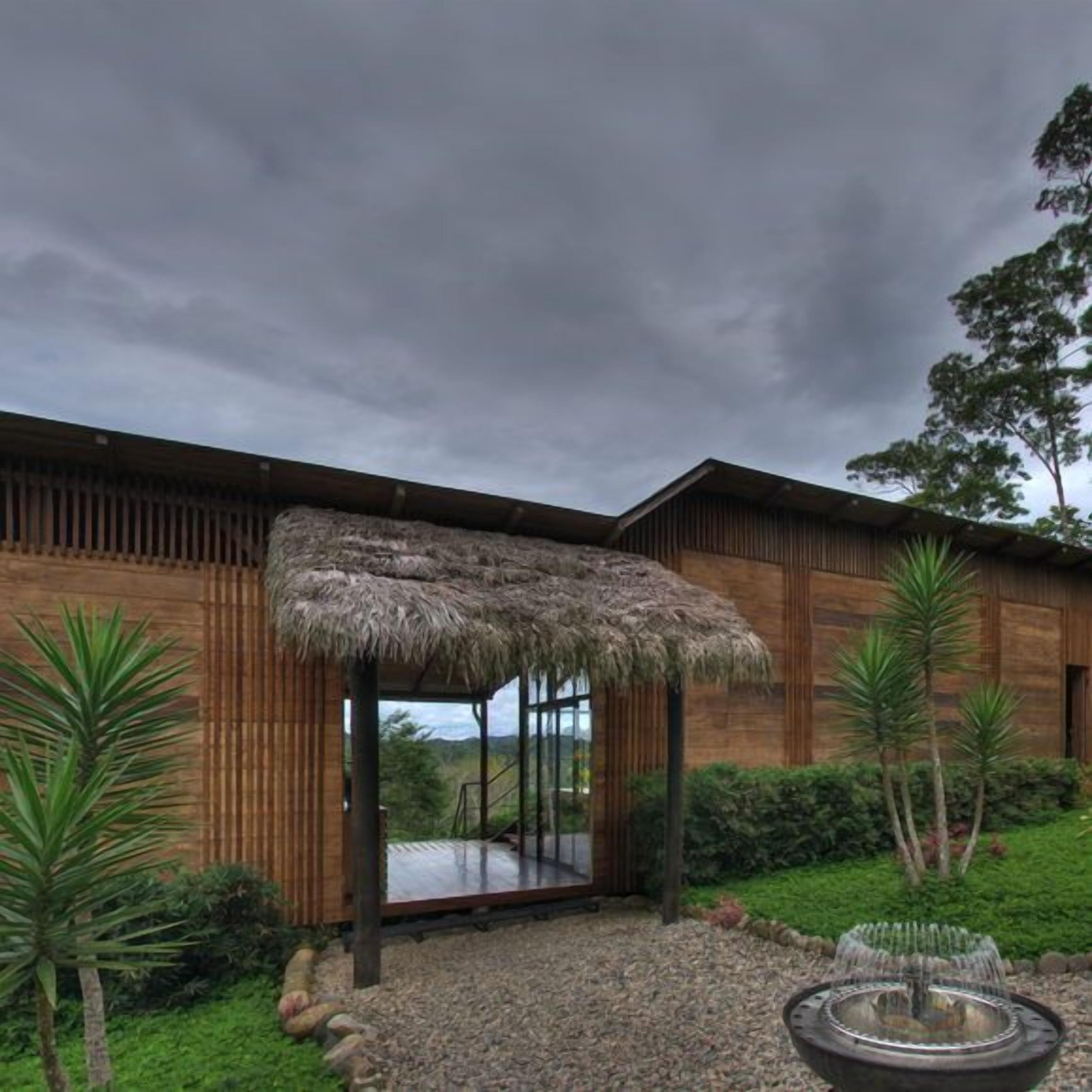 A modern building with a thatched-roof structure, wooden walls, and a gravel pathway.