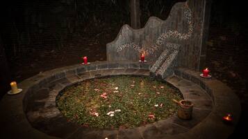 A stone fountain with water and flowers, surrounded by candles.