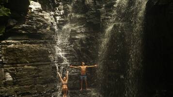 Una cascada en un entorno rocoso con dos personas admirando la vista.