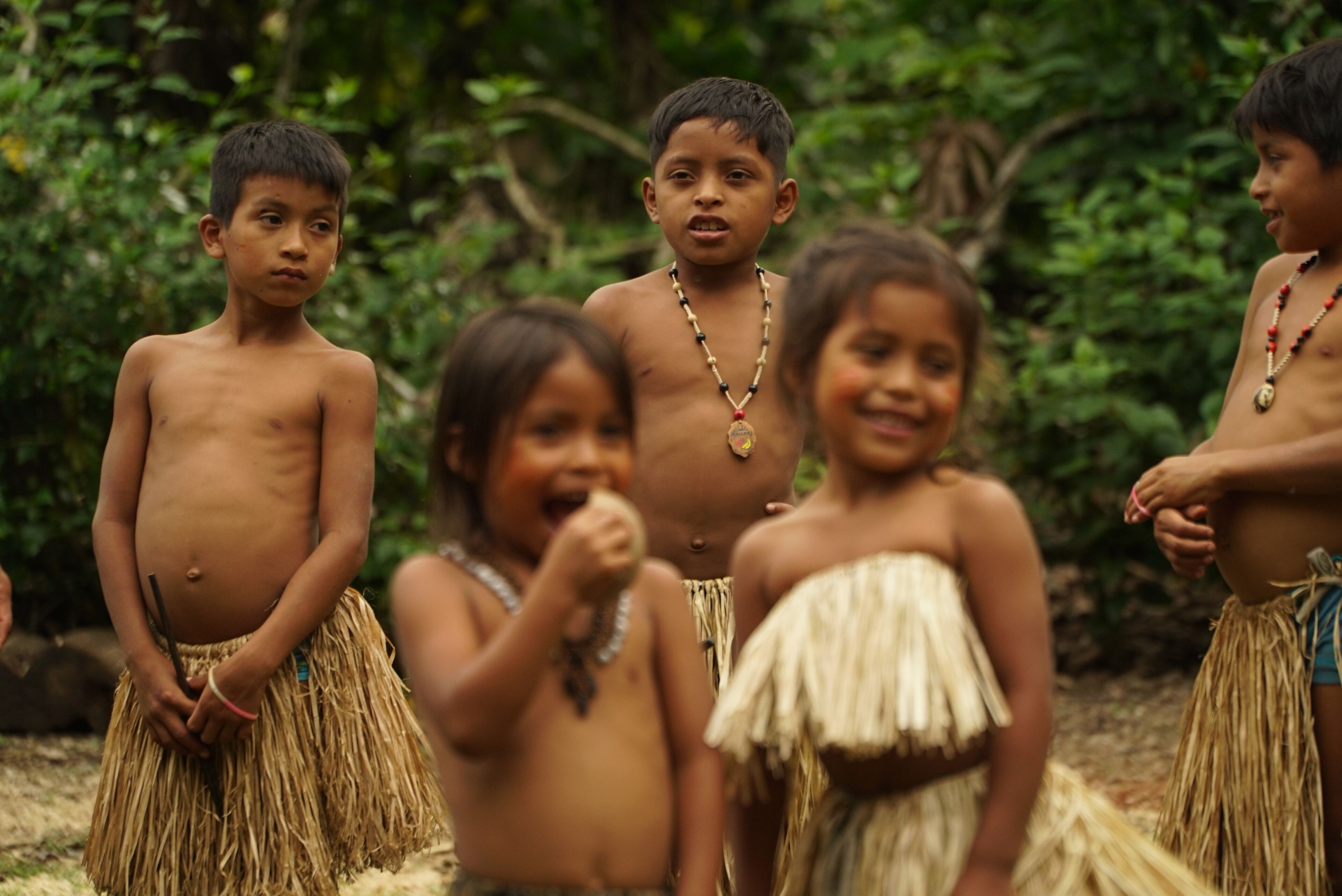 Un grupo de niños vestidos con trajes tradicionales al aire libre.