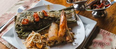 Un plato de comida con pescado, verduras y salsa sobre una mesa de madera.