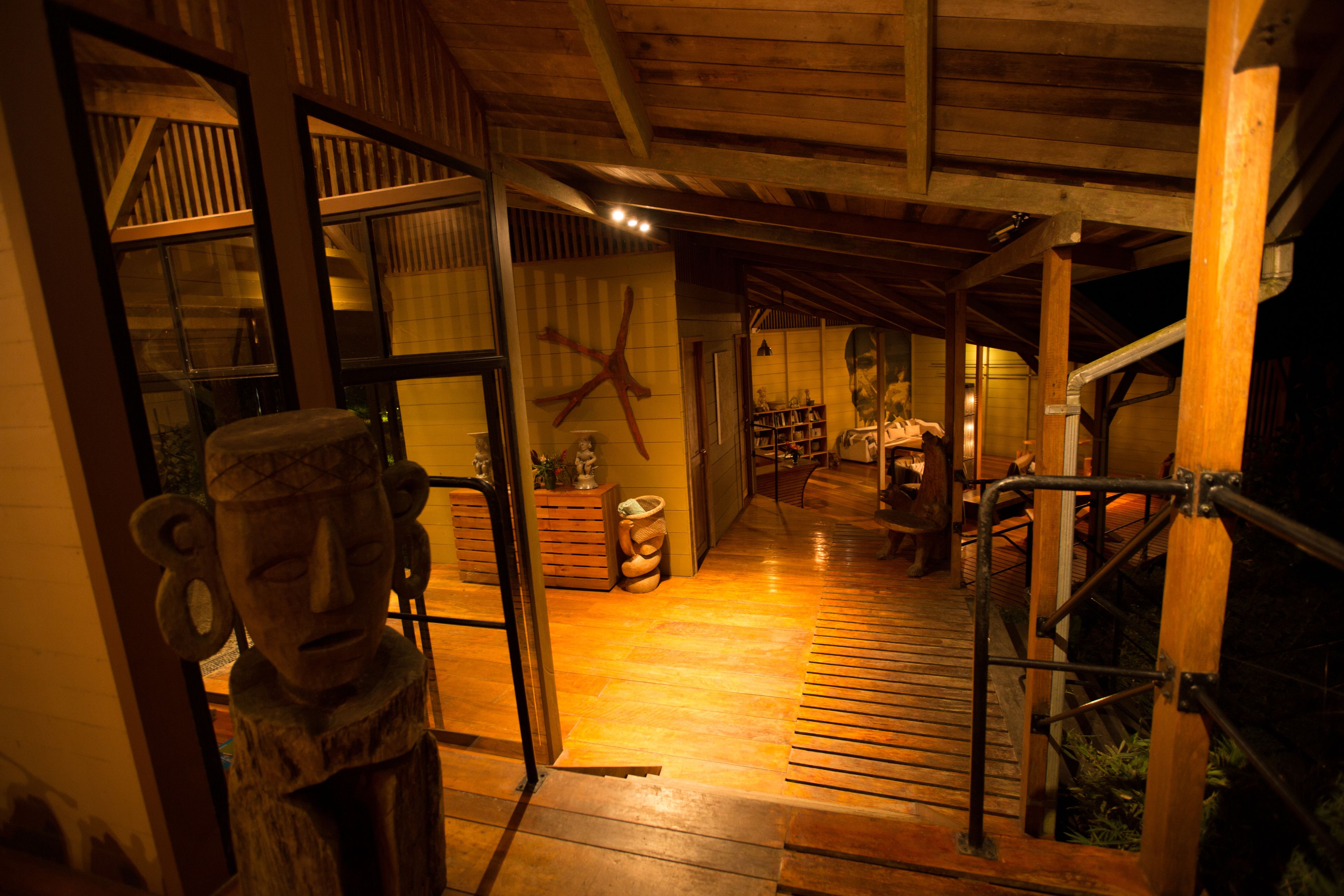 A wooden interior with a staircase, a wooden door, and a statue.
