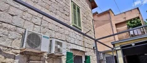 A stone building with air conditioning units, a gated entrance, and a clear blue sky.