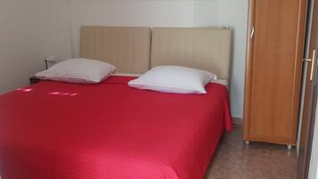 A bedroom with a bed, a wardrobe, a wall-mounted air conditioner, a ceiling light, and a framed picture.