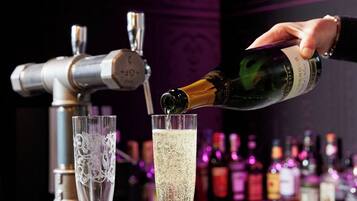 A bar setting with a hand pouring champagne into a glass.