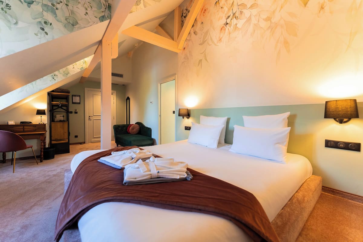 Une chambre d’hôtel avec un grand lit, un bureau, une chaise et un escalier menant à un étage supérieur.