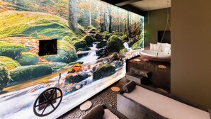 Ein Wellnessbereich mit Wandgemälde eines Waldlaufs, einem Massagesessel und einer Badewanne.