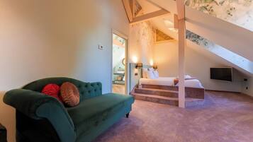 Ein Zimmer mit einem grünen Sofa, einem Bett, einem Fernseher und einer Treppe zu einer oberen Ebene.