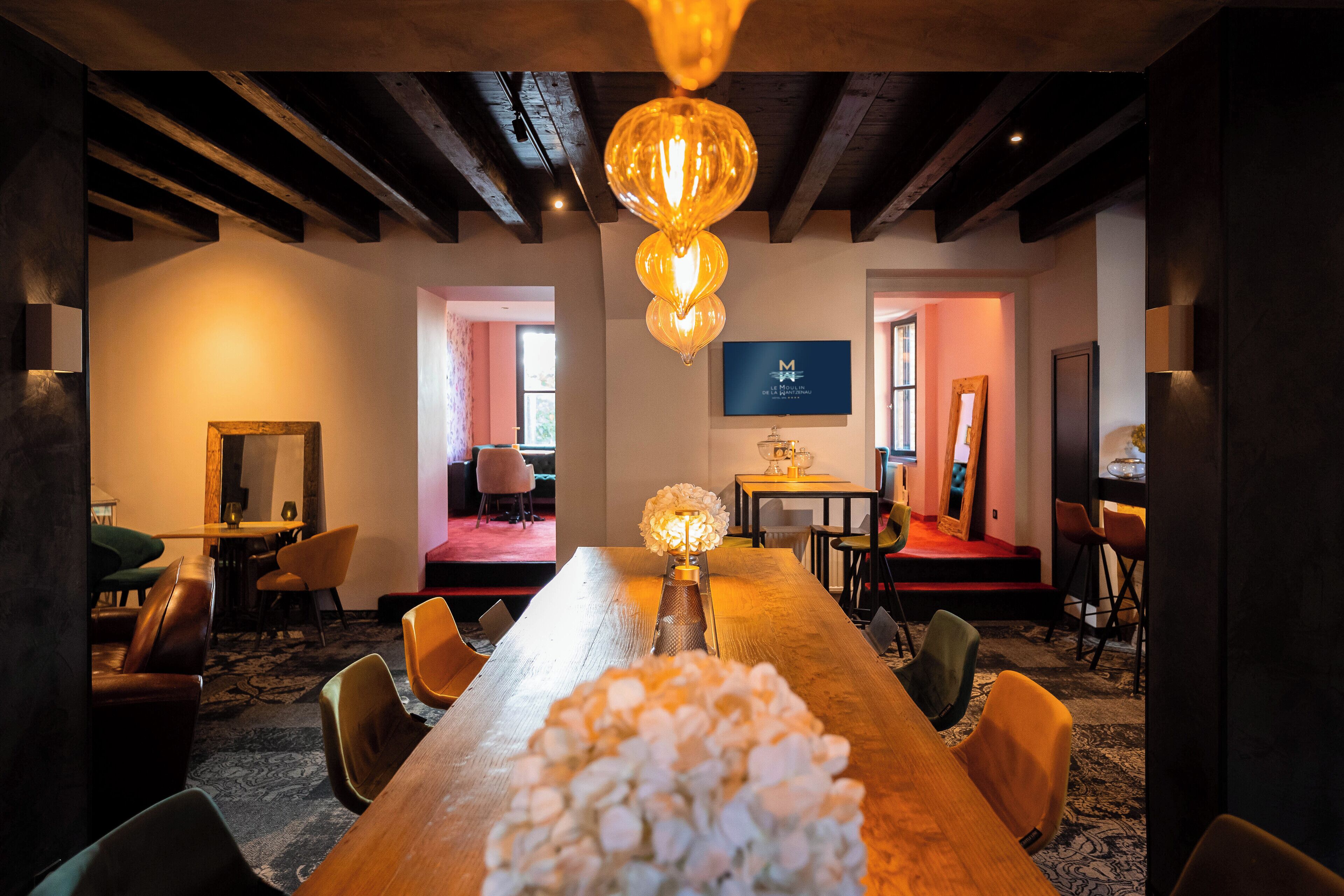 A conference room with a long table, chairs, a chandelier, and a television screen.