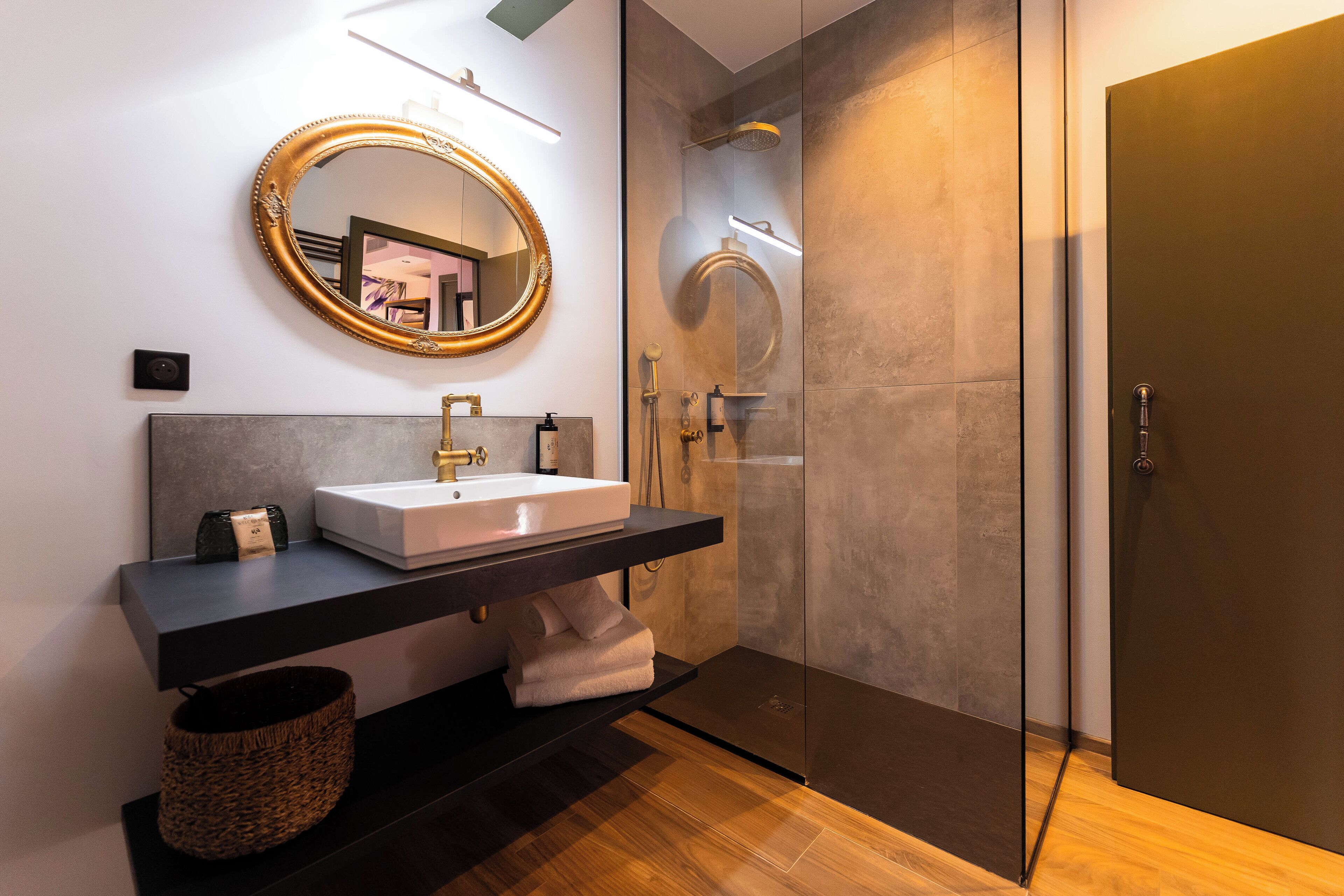 Une salle de bain moderne avec un grand miroir, un lavabo et une douche à parois de verre.