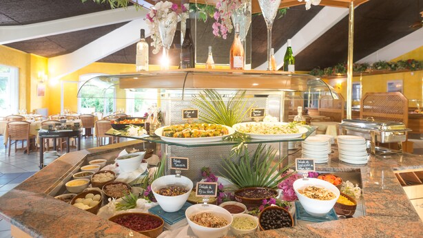 A buffet with various food options, including salads, fruits, and desserts, arranged on a marble counter. - Pascal Paoli (Aregno)