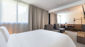 Une chambre d’hôtel avec un grand lit, un bureau, une chaise et une armoire.