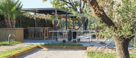 An outdoor patio area with seating, a covered structure, and a table with chairs.