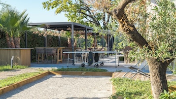 Un patio al aire libre con mesas, sillas y una estructura cubierta.
