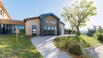 A modern building with a sign reading 'Kyriad' and a reception desk.