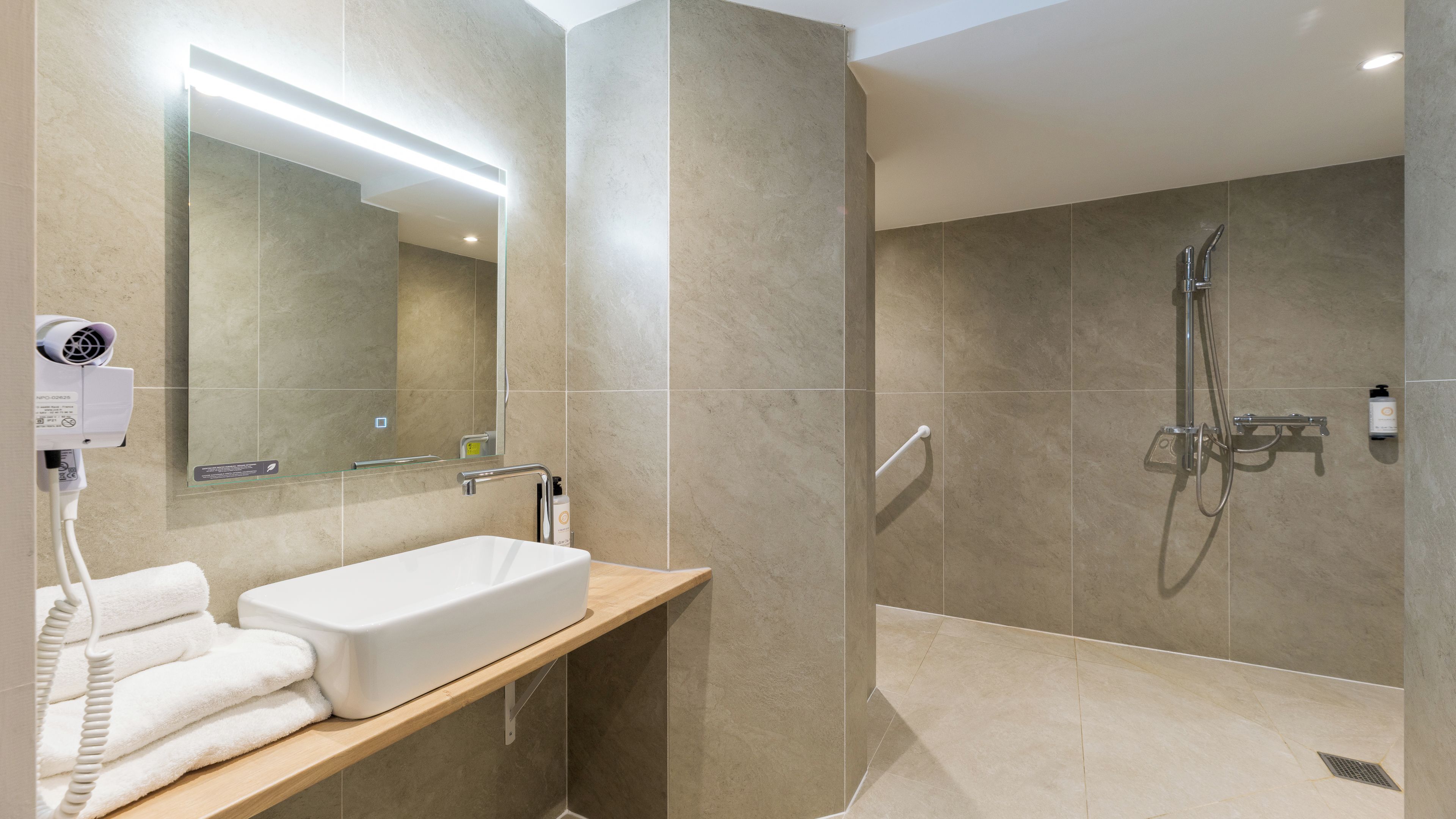 A modern bathroom with a large mirror, a sink, and a shower area.