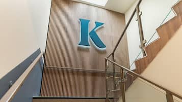 A modern staircase with a wooden panel wall and a large 'K' sign.