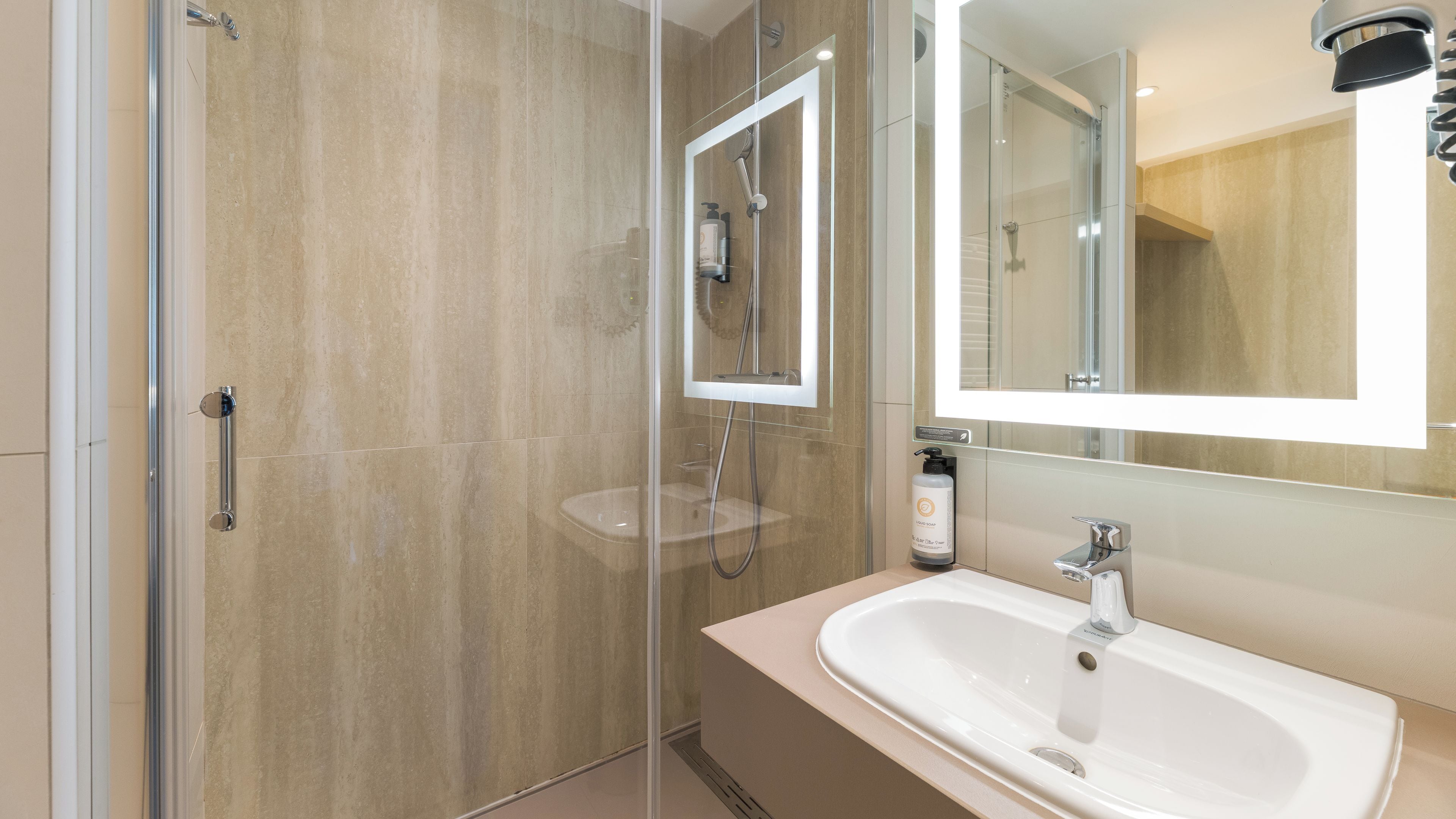 A modern bathroom with a glass-enclosed shower, a sink with a mirror, and a handheld showerhead.
