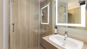 Une salle de bain moderne avec une douche à parois de verre, un lavabo avec un miroir et une douchette à main.