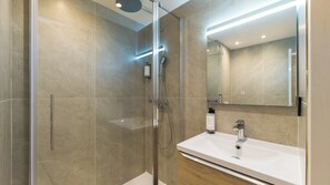 A modern bathroom with a glass-enclosed shower, a white sink, and a large mirror. - Kyriad - L'Isle-D'Abeau Bourgoin-Jallieu (L'Isle-d'Abeau)