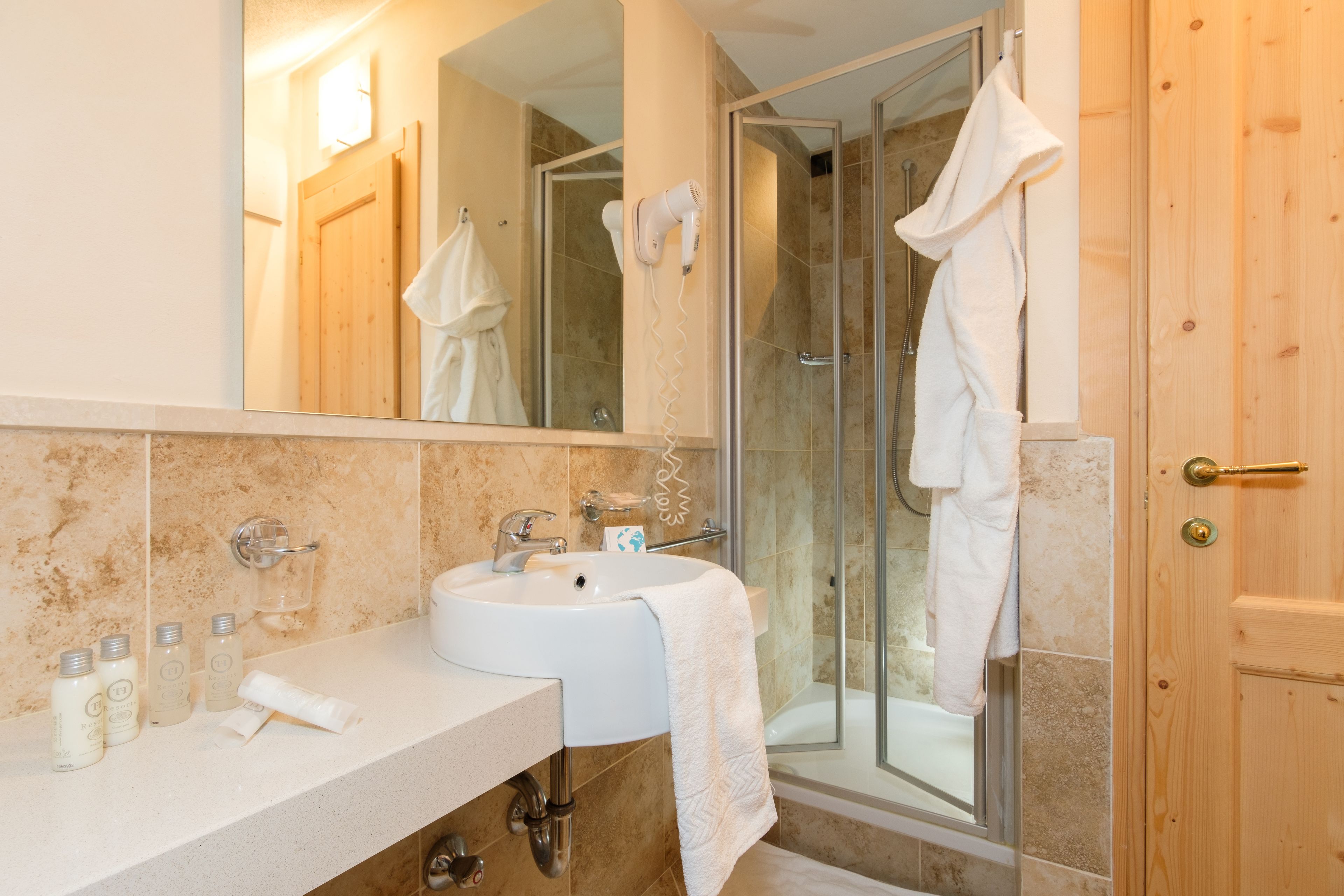 A bathroom with a sink, mirror, and glass shower enclosure.