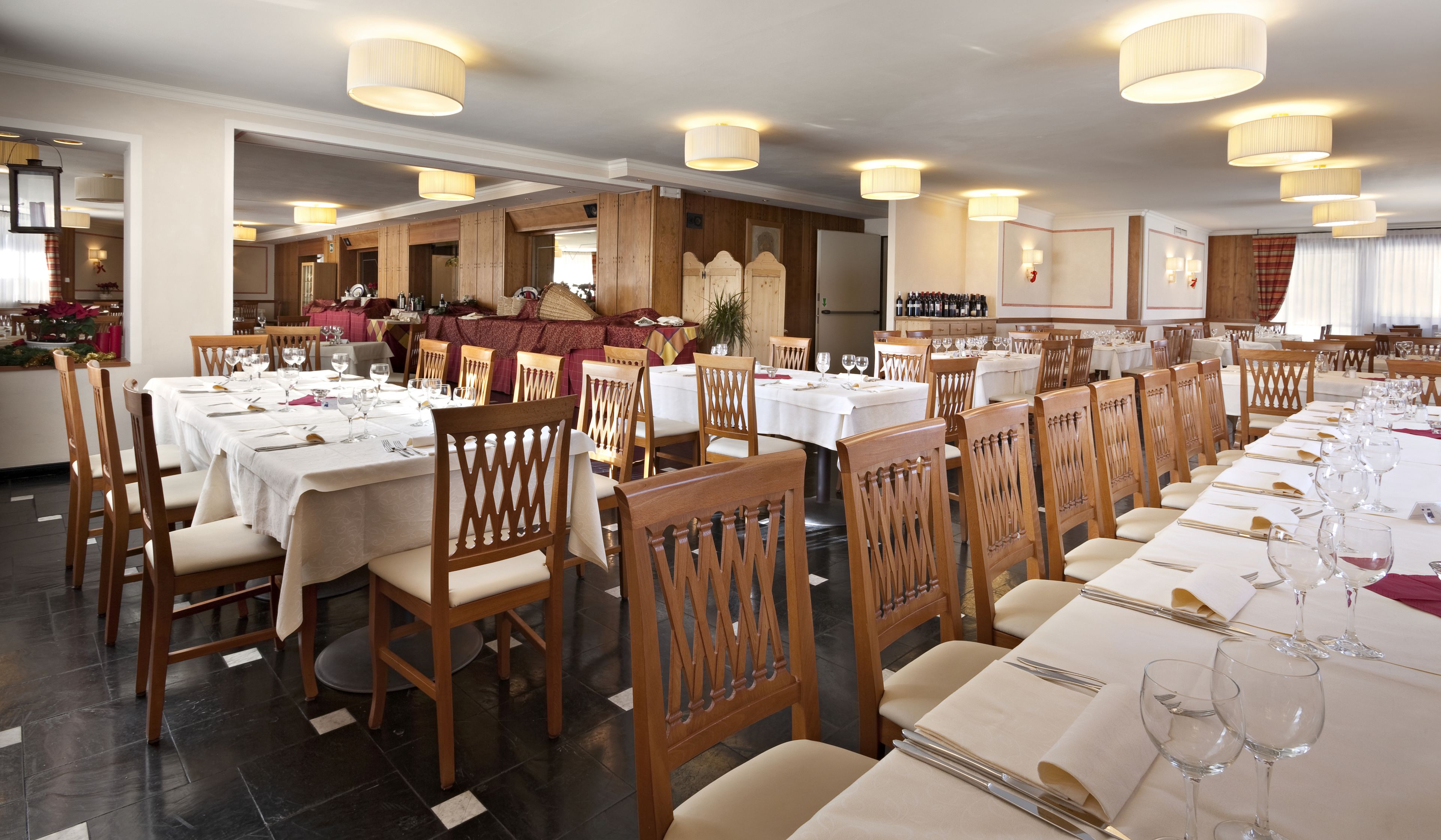 Un ristorante con diversi tavoli, sedie di legno e lampadari a sospensione.