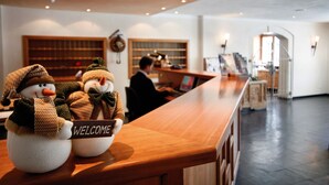 A reception area with a wooden counter, two snowman decorations, and a welcome sign. - TH Corvara - Greif Hotel (Corvara in Badia)