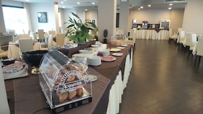 Un'area ristorazione di un hotel con un buffet ricco di cibi diversi e un angolo per il caffè.