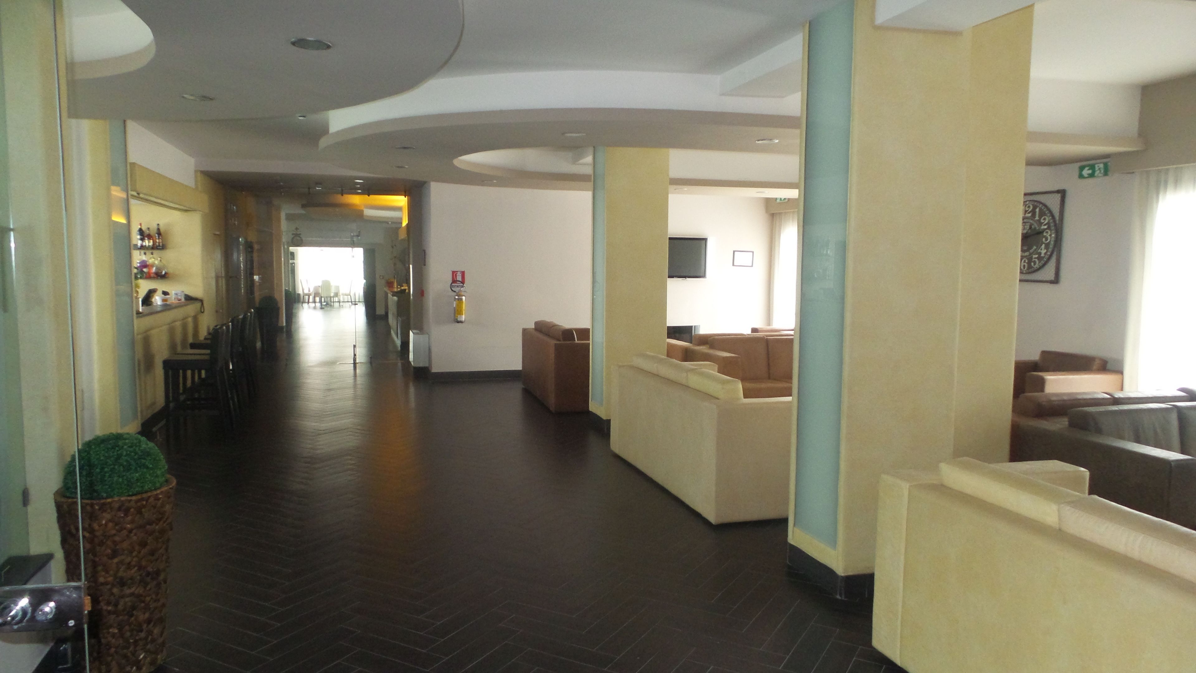 A hotel lobby with a long corridor, seating areas, and a reception desk.