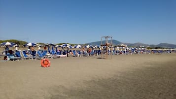 Una playa cerca, sillas reclinables de playa, sombrillas