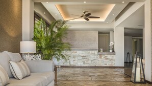 A modern living room with a stone fireplace, a ceiling fan, and a large potted plant. - Almyra Hotel (Kefalonia)